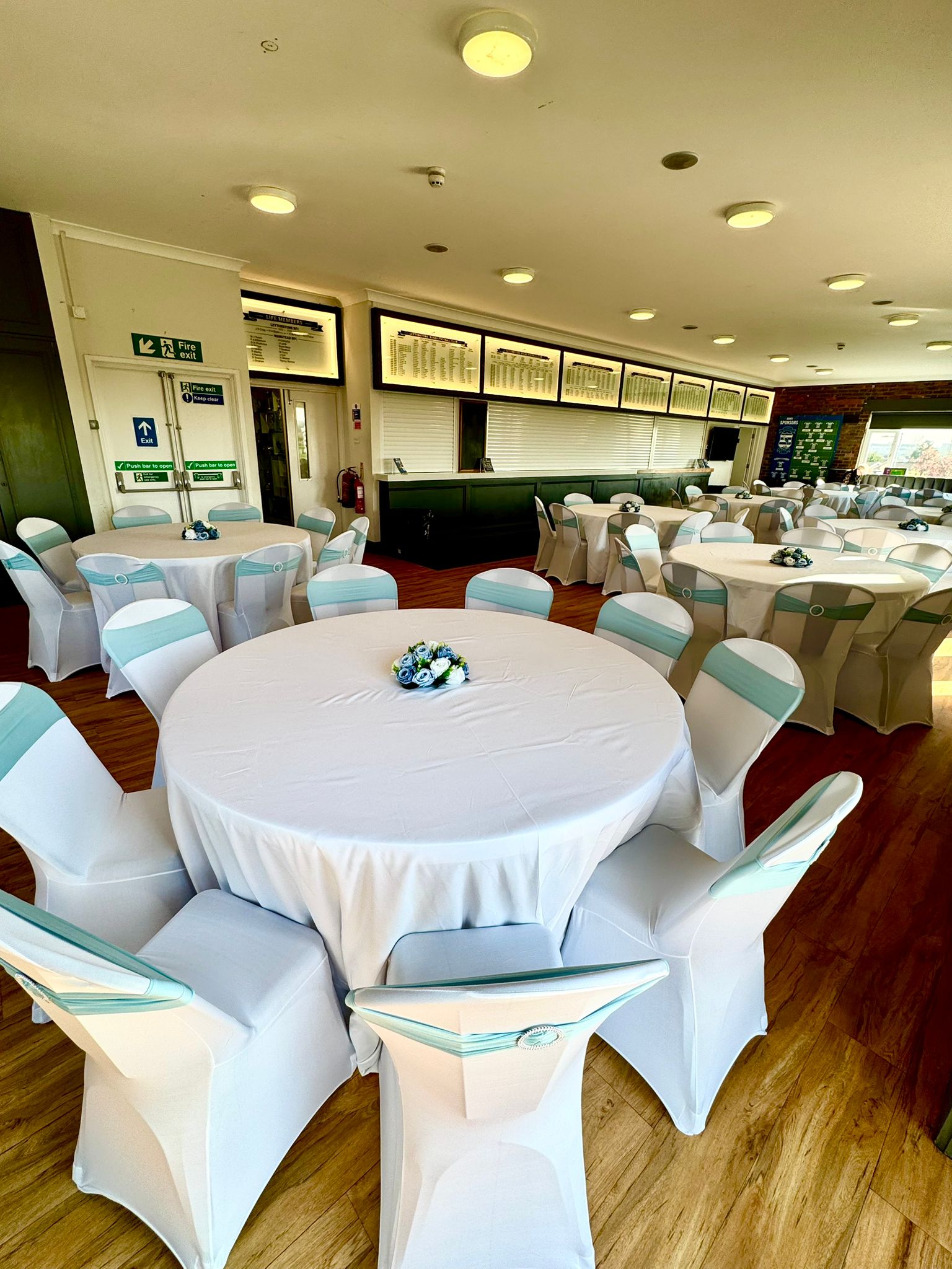 Close-up of a banquet table setup with light blue sashes and floral centerpieces